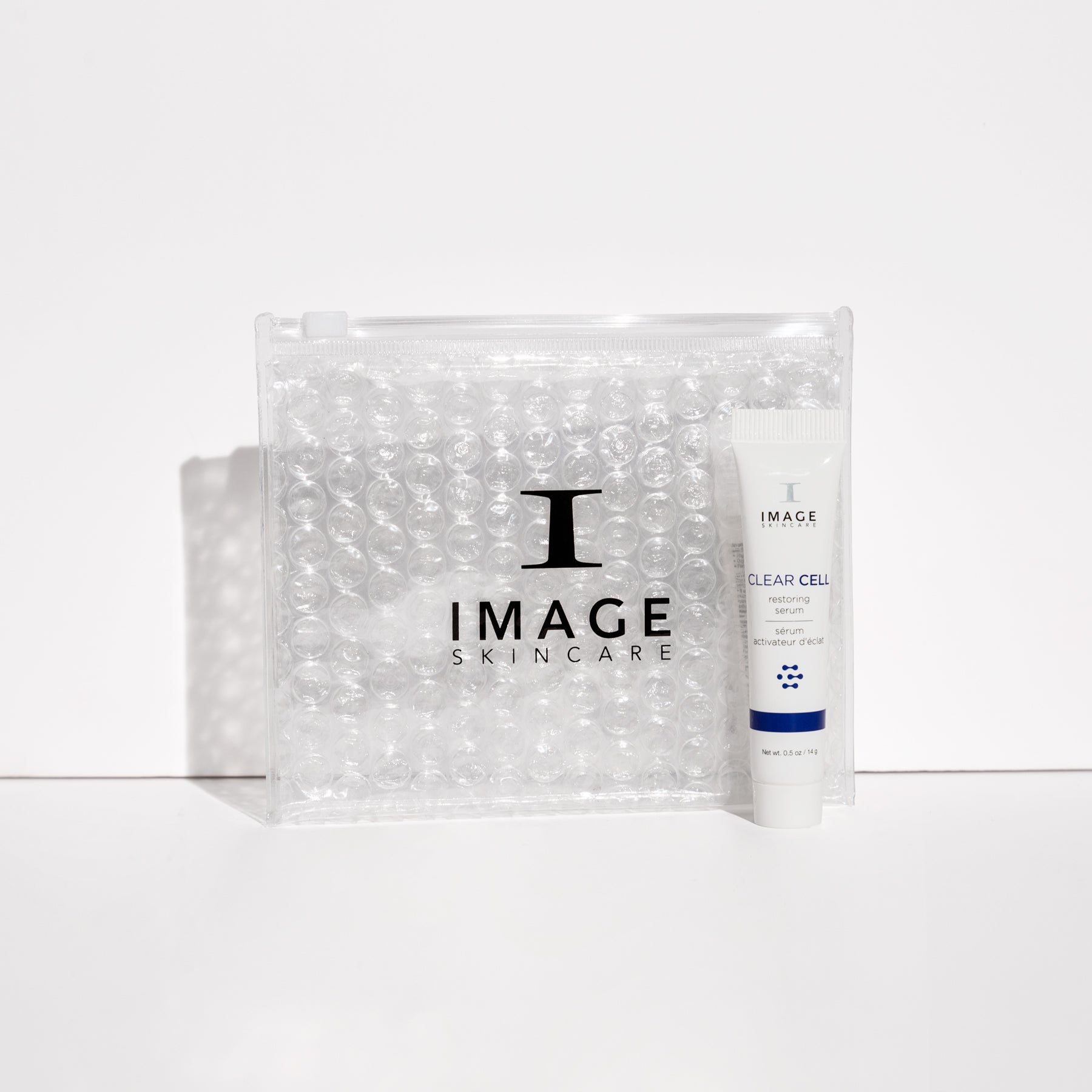 Clear cell restoring serum travel size next to clear bubble bag